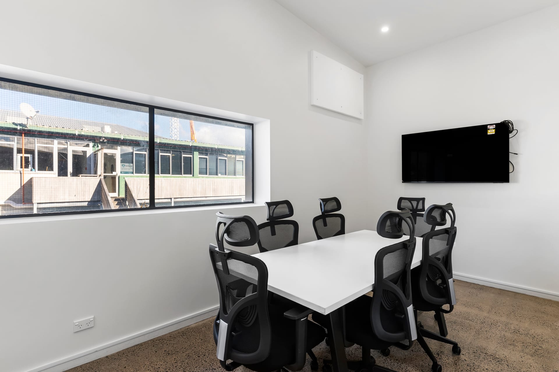 Six-person meeting room with wall-mounted TV and outlook at Thinkspace Morningside