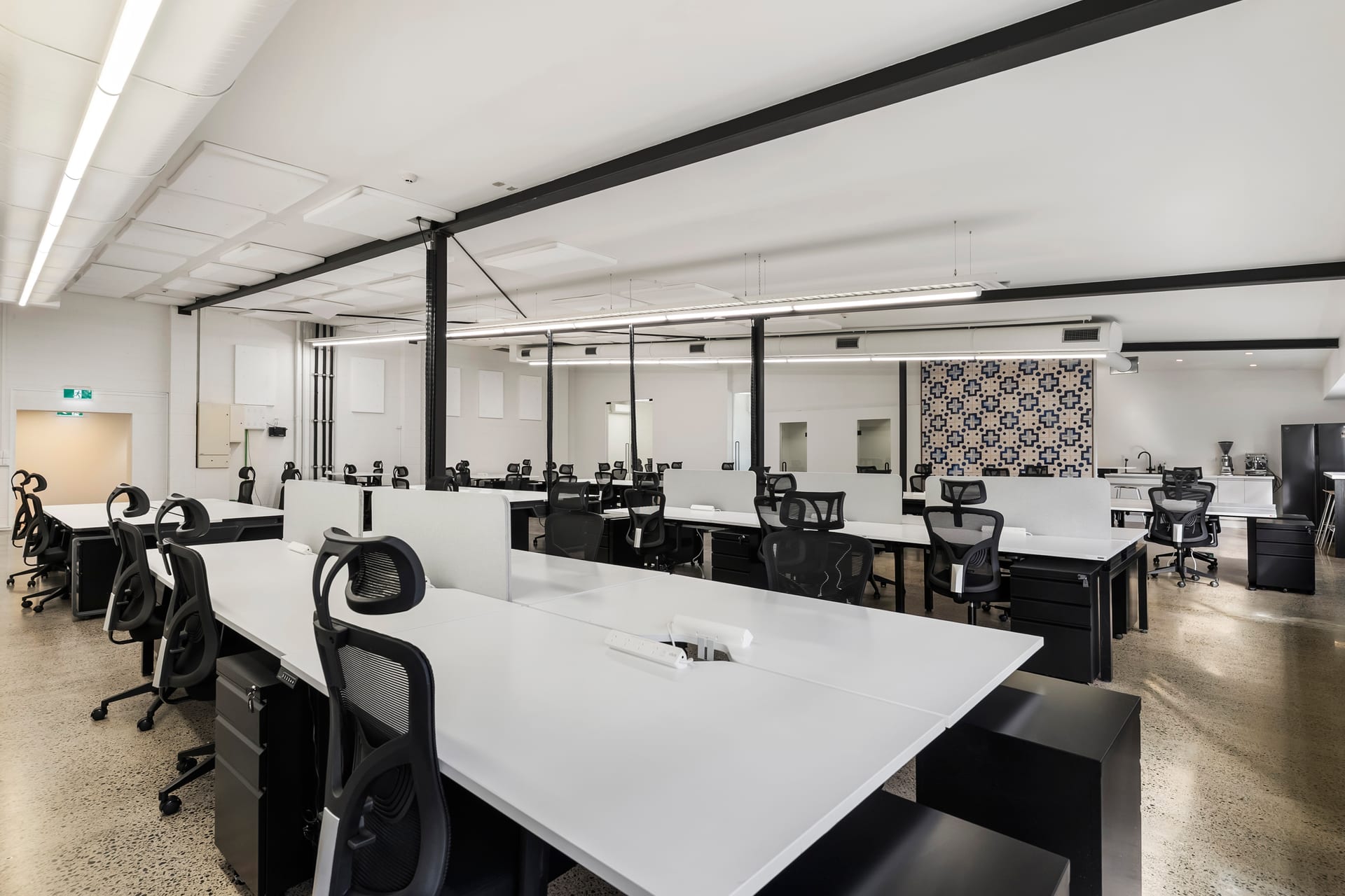 Shared workspace with glass-partition offices behind at Thinkspace Morningside