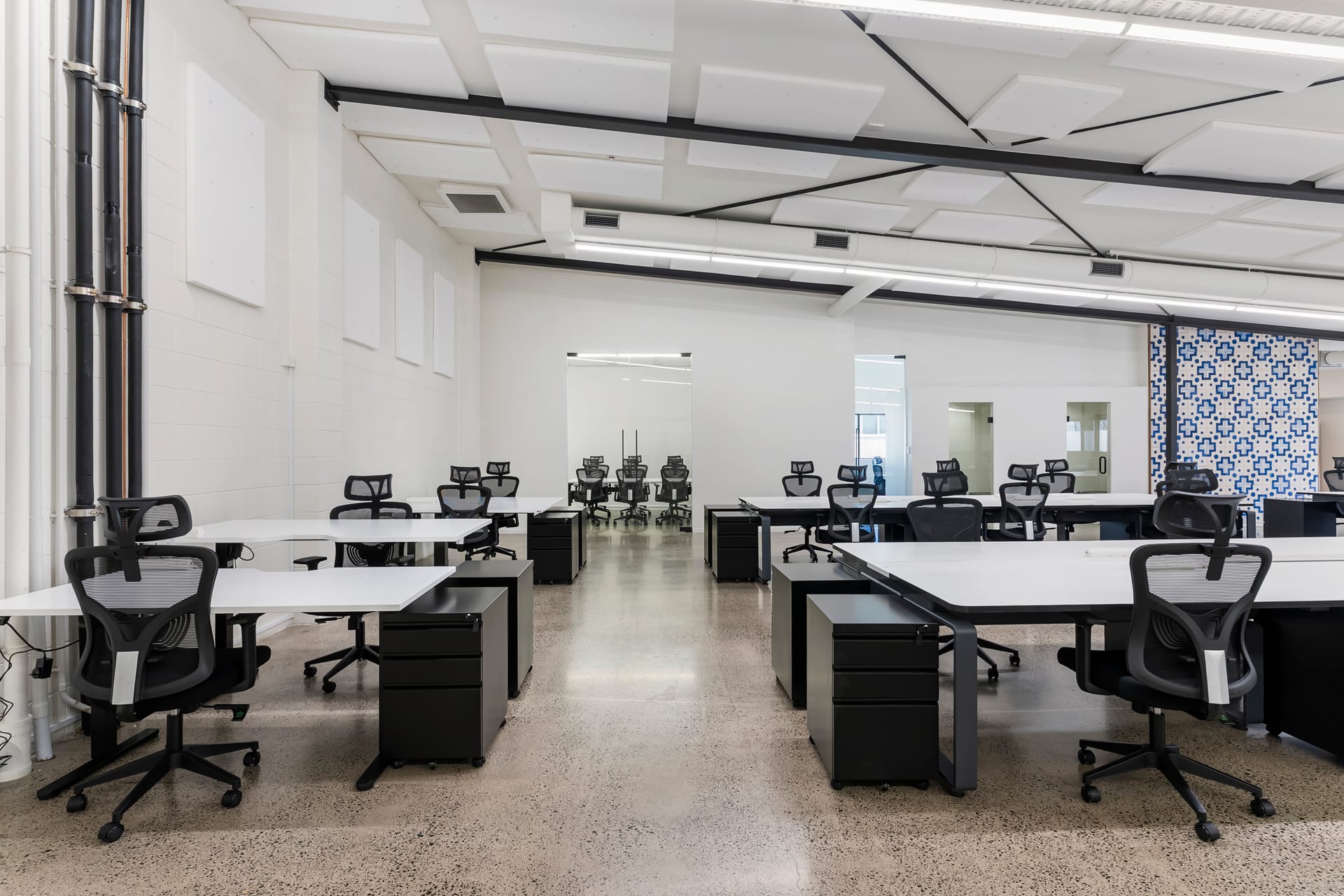 Dedicated desks beside a decorative tiled feature wall at Thinkspace Morningside